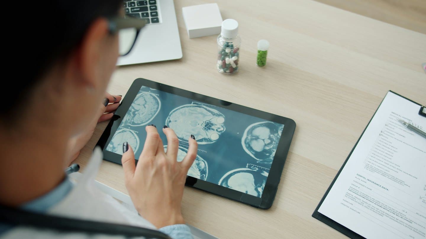 Medico che esamina scansioni cerebrali su un tablet alla scrivania.